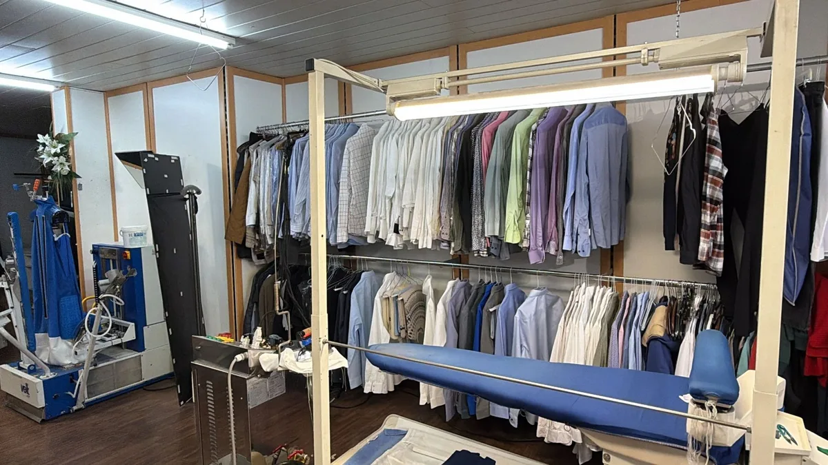 Bügelbereich mit Hemden und Kleidung auf Stangen